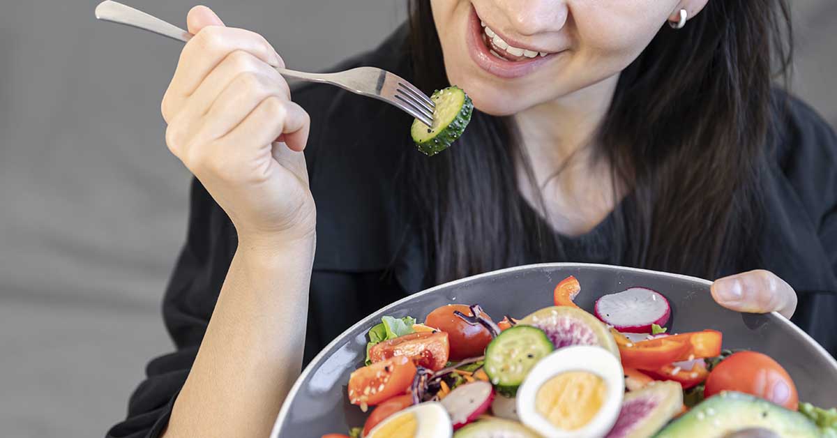 Nutrologia na endometriose: tratando a inflamação de dentro para fora 3 imagem de uma mulher comendo em um prato saudável, com ovos, vegetais e mais
