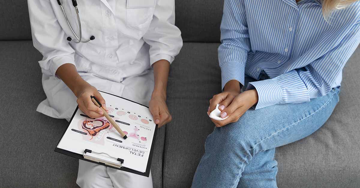 Congelamento de óvulos em São Paulo: quanto custa e onde fazer? 2 Médica ginecologista falando e explicando algo a paciente com uma prancheta na mão e sentadas em um sofá